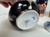 a hand that is holding a black and gold vase