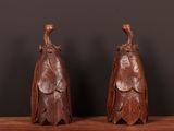 une paire de figurines d'oiseaux en bois sculpté posées sur une étagère en bois