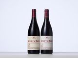 two bottles of red wine sitting next to each other on a table