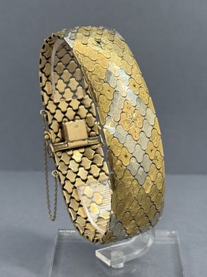 a close up of a gold bracelet on a clear stand