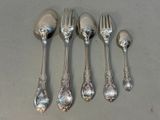 five silver spoons and a fork on a table