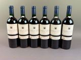 six bottles of wine are lined up in a row on a table