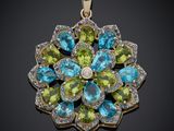 un gros plan d'un pendentif en forme de fleur verte et bleue sur fond noir