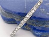 un gros plan d'une broche en forme de barre sertie de diamants sur une pierre bleue