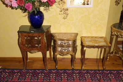 un vase de fleurs posé sur une table, à côté de deux tables d'appoint