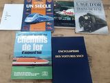 several books on a table with a train in the background