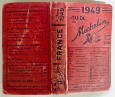 an old book with a red cover sitting on top of a table
