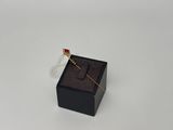 une petite boîte noire ornée d'une broche dorée et rouge