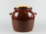 un pot marron avec un couvercle posé sur une surface blanche