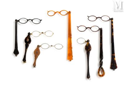 several pairs of glasses and a pair of scissors on a white surface