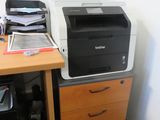 a printer sitting on top of a desk next to a filing cabinet