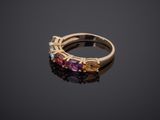 a gold ring with multi colored stones on a black surface