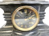 une horloge noire surmontée de chiffres romains