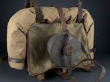 an old backpack with a hat on top of it sitting on a table
