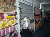 many fabrics on display in a store with a mannequin in the foreground