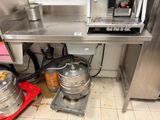 stainless steel counter top with kegs under it in a commercial kitchen