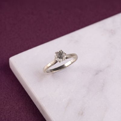 une photo d'une bague en diamant posée sur une surface en marbre