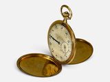 une montre de poche en or posée sur une surface blanche
