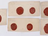 quatre morceaux de cire sur une feuille de papier, avec quatre cachets de cire différents