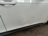 the front door of a white car with a dent on it