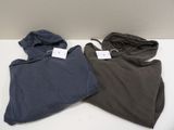two pairs of hoodies sitting on top of a white table