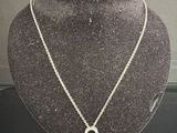 silver necklace with a circle pendant on a mannequin base