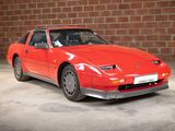 an image of a red sports car parked in front of a brick wall
