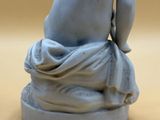 a small statue of a naked man sitting on a rock