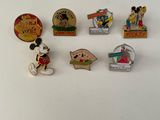 Plusieurs pin's Disney sont disposés sur une surface blanche