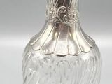 une image représentant un flacon de parfum en argent et en verre sur fond blanc