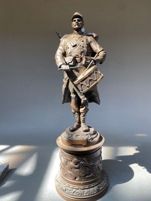 une statue en bronze représentant un homme tenant un fusil
