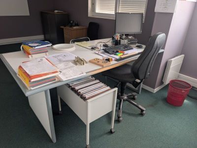 a desk with a lot of papers on it and a chair