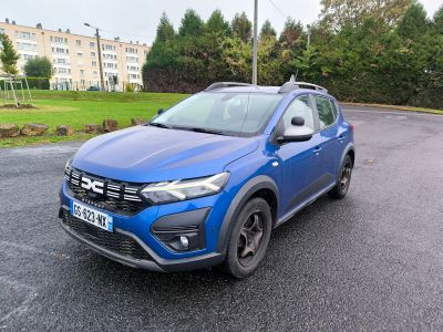 La voiture bleue est garée sur le bord de la route, dans le parking.