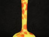 an orange and yellow vase sitting on top of a black table