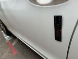 a sticker on the door of a white car that is parked in a parking lot