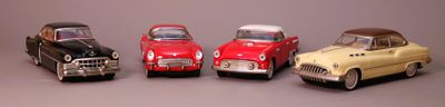 several toy cars are lined up in a row on a gray surface