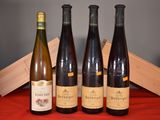Quatre bouteilles de vin sont alignées sur une table rouge