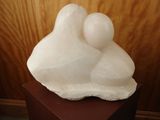 a white sculpture of a mother and child on a wooden stand