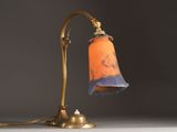 an orange and blue lamp on a table next to a gray wall