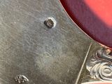 une cuillère en métal avec un manche en métal posée sur une surface rouge