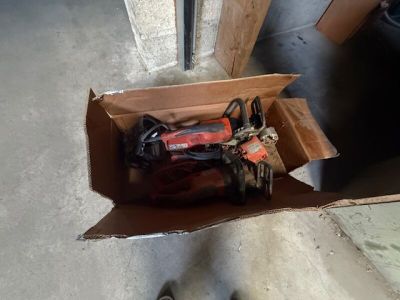 une boîte en carton posée par terre, contenant des outils