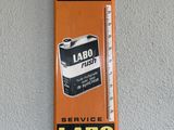 an orange and black sign hanging on a wall with a thermometer on it