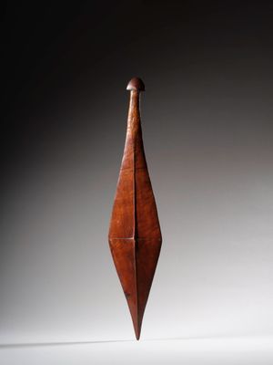 une sculpture en bois représentant un oiseau au long cou, posée sur une surface blanche