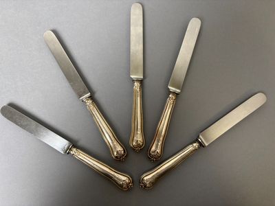 four silverplated knives are arranged in a circle on a table