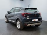 the back of a blue car in a showroom with a black floor