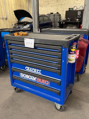 La boîte à outils bleue se trouve dans le garage avec d'autres outils.