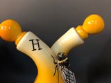 a yellow vase with a bee on top of it