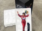 une figurine représentant un homme en combinaison de course, dans une boîte
