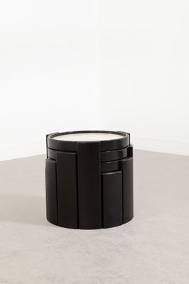 une table basse noire posée à même le sol, près d'un mur blanc