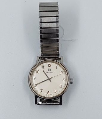 une montre-bracelet en argent avec un cadran blanc posée sur une surface blanche